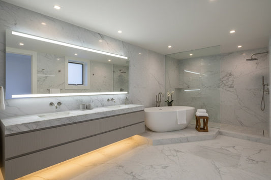 Baño moderno con iluminación LED: aplique lineal sobre espejo, luz ambiental bajo mueble flotante y downlights empotrados IP54